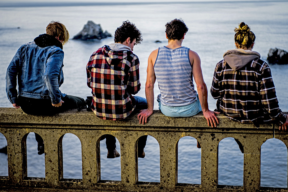 Photo of Four Young Adults, Sitting on a Pier -Photo by Sammie Vasquez