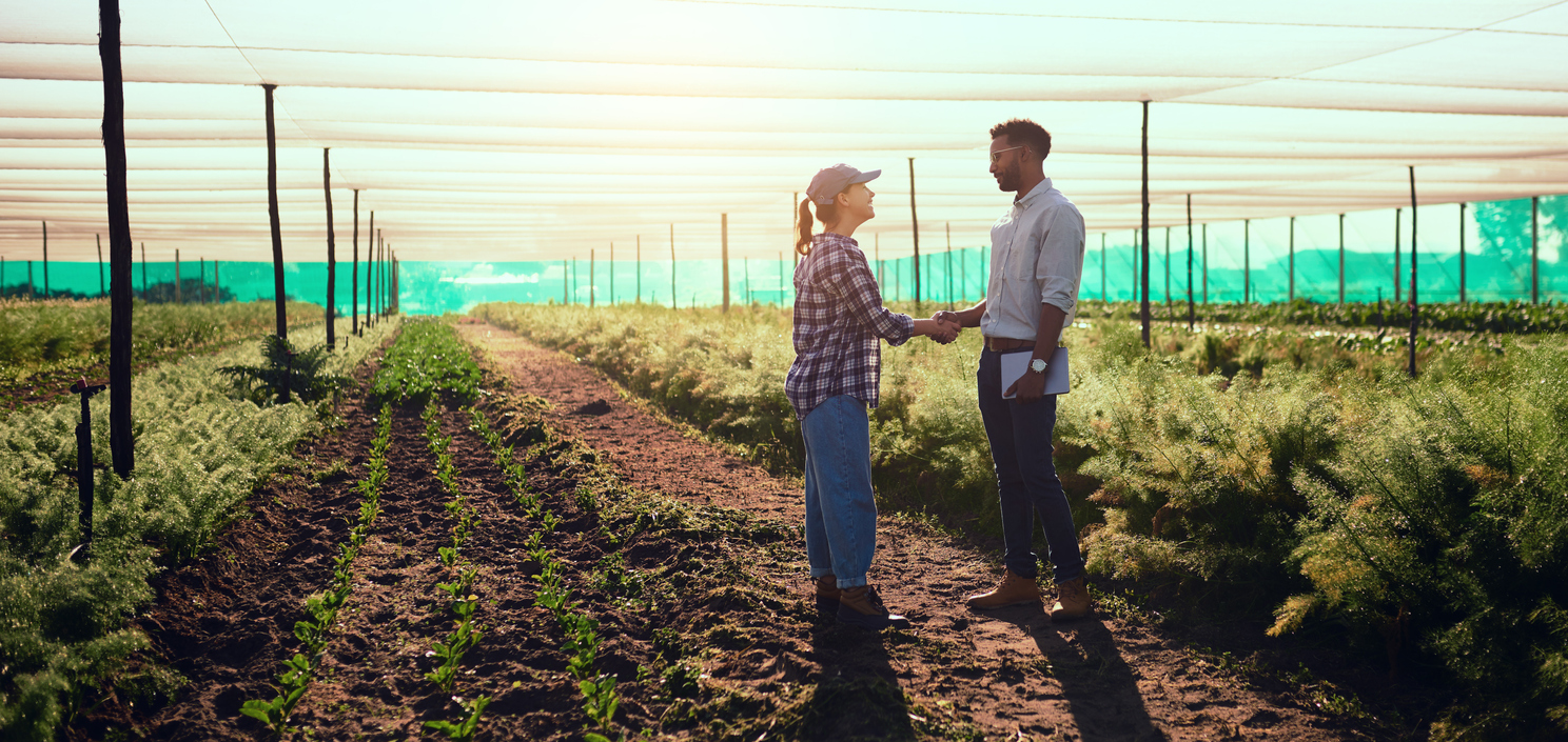 Farmer and extension office agent shake hands in field