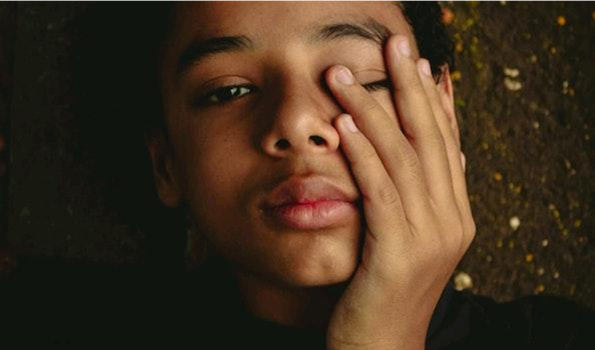 Black boy with hand covering left eye