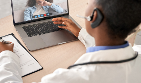 Telehealth Story Image _ A practitioner in a white coat speaks to a patient via video call. 