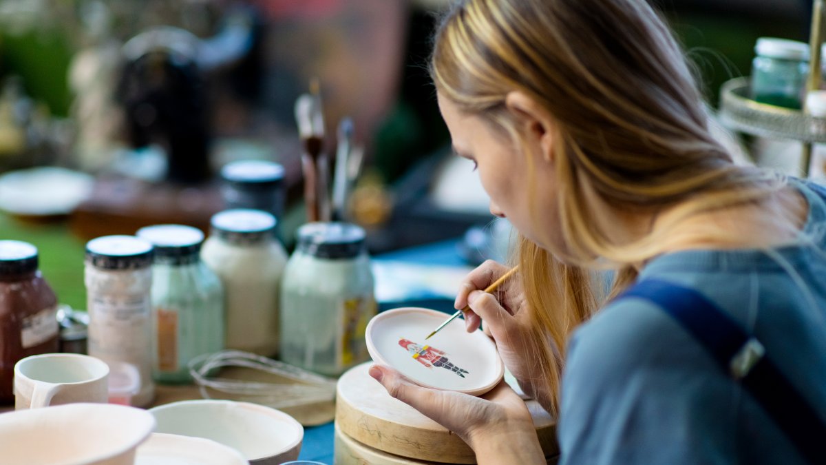 woman painting on ceramic