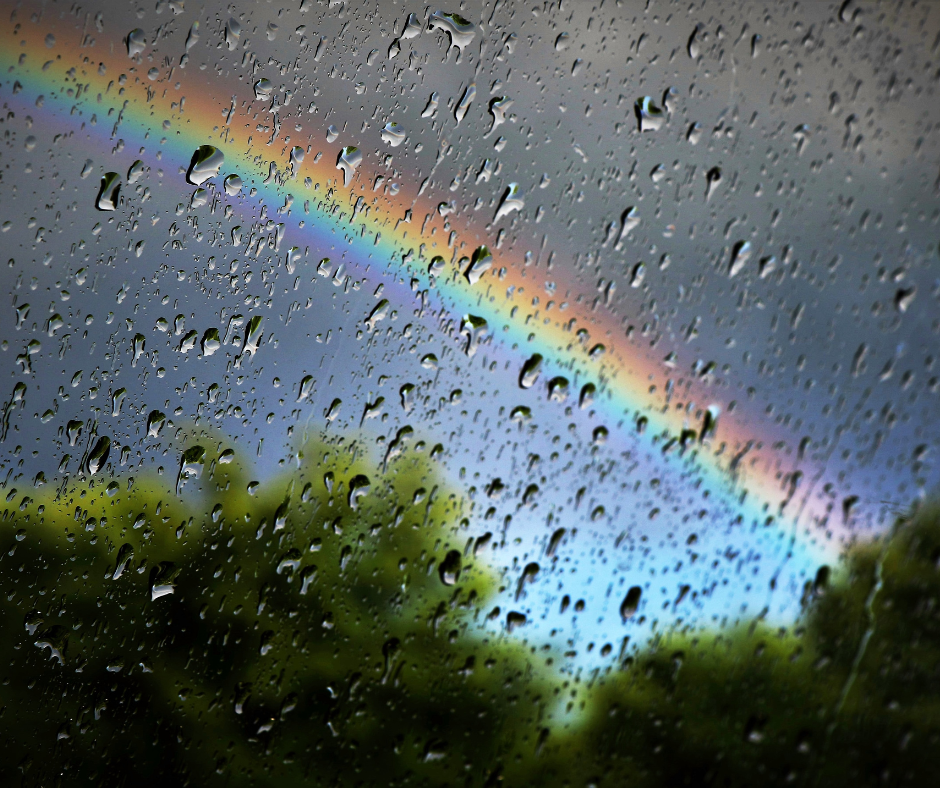 A window with raindrops and a rainbow.